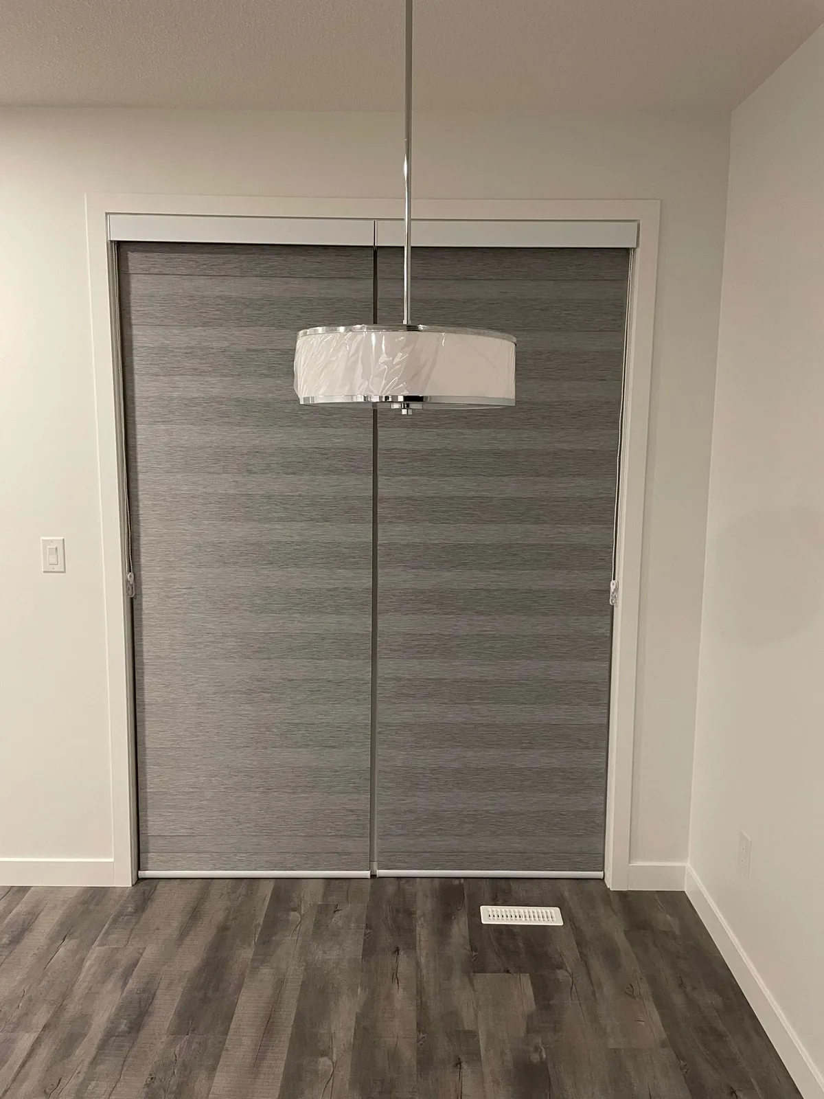 Two-piece grey roller blinds installed over a patio door in Edmonton